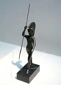 Statuette en bronze d'un soldat avec un casque à crête et une lance.