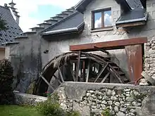 Photo de la façade d’un ancien moulin à eau avec sa roue.