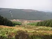 Photographie des pentes boisées d'une haute colline.