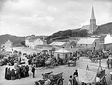 photographie ancienne d'un village animé par des passages de charettes.