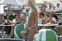 Sur la plage, une femme blonde debout portant un microkini blanc