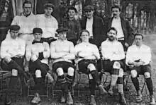 Photo en noir et blanc d'une équipe de football à la chemise blanche posant sur deux rangs.