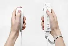 Une télécommande Wii et une manette Nunchuk, deux manettes de jeux vidéo de forme allongée en plastique blanc.