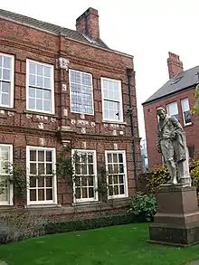 Statue dans le jardin gazonné d'une maison en brique.