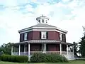 Maison en brique parfaitement octogonale avec véranda, toit en pente et lanterne.  Wilcox Octagon House, Camillus, New York (construite en 1856).