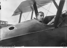 Photographie noir et blanc d'un homme dans le cockpit de son avion, seule sa tête dépasse et regarde l'objectif.
