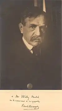 Photographie de Paul Bourget de face. Veste noire, dédicace à M.Willy signée de Bourget sous la photographie.