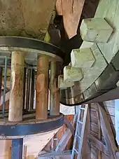 Photo d'un mécanisme composé d'une roue dentée et d'un fuseau en bois.