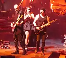 Trois membres d'un groupe de rock, dont deux hommes et une femme, jouant sur scène