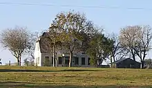 Vue d'une maison blanche masquée partiellement par un arbre