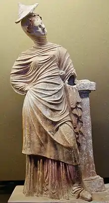 Jeune femme drapée appuyée contre un pilier, production de Tanagra, fin IIIe siècle av. J.-C. ou début IIe siècle av. J.-C.. Musée du Louvre.