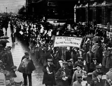 Photographie en noir et blanc d'une manifestation de suffragettes dans les rues de Londres.