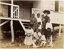 Photographie représentant une femme européenne et un groupe de femmes et d'enfants autochtones, vêtus à l'occidentale.