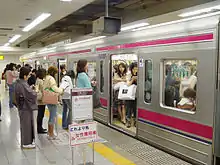 Photo couleur montrant des femmes sur un quai de gare, devant une rame de métro pleine de représentantes de la gent féminine.