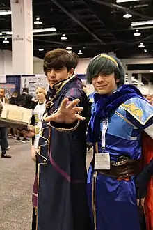 Deux personnes costumées, l'une aux cheveux bleus et portant une épée, alors que le second porte un manteau sombre et un grimoire.