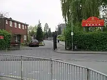 Photo de l'entrée d'un établissement scolaire avec un bâtiment en briques rouges sur la gauche.
