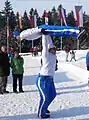 Fabian Ebenoch tenant Evelyn Insam au-dessus de lui les bras tendus, la tenant par les hanches, elle le corps tendu horizontalement simulant un saut à ski sur tremplin