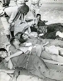 Patton se penche au-dessus d'un groupe d'hommes allongés sur le sol