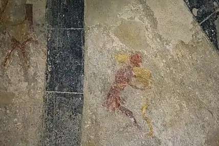 Fresque médiévale très abîmée montrant deux hommes en train de lutter.