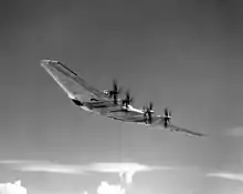 Photo en noir et blanc d'une aile volante XB-35 en vol, dotée de plusieurs moteurs à hélice.