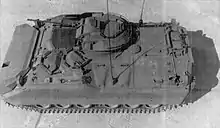 photographie en noir et blanc montrant de dessus et légèrement de profil un véhicule blindé à chenilles avec une tourelle