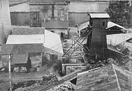 Photo en noir et blanc montrant en vue plongeante un site industriel avec un chevalement et des cheminées.