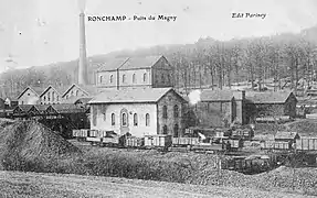 Carte postale. Bâtiments industriels dominés par une grande cheminée. Au premier plan un train.