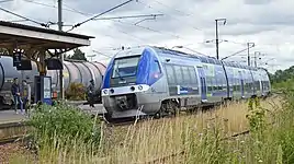 Une rame X 76500 à quai, pendant qu'un train de fret franchit la gare.