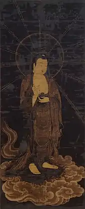 Photo couleur d'une peinture sur soie d'une représentation d'un bouddha, debout sur un nuage, sur fond noir.