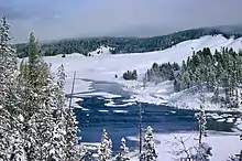 Photographie montrant le bord d'un cours d'eau glacé et enneigé.