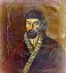 Portrait d'homme, barbu, vêtu d'une tunique. Une chaîne pend à sa droite.