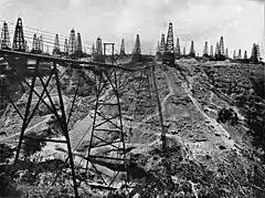 Photo en noir et blanc d'une plaine criblée de puits de pétrole.