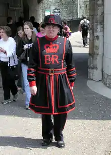 Photographie en couleurs d'un homme portant un costume noir brodé de rouge.