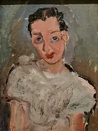 Sur fond gris, portrait en buste d'une femme brune avec chemisier entre blanc et gris perle.