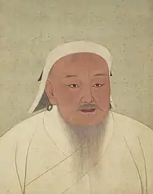 Portrait d'un homme grisonnant. Il porte une longue barbe et des anneaux à ses oreilles. Il est vêtu d'un chapeau et de vêtements blancs.