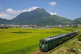 Vue du mont Yufu depuis le sud-ouest avec au premier plan un train quittant Yufuin.