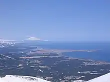 Vue aérienne d'une partie de Kounachir avec le Tyatya, son point culminant, à l'horizon.