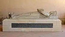 Photo d'un gisant en pierre d'une femme vêtue d'une longue robe avec les mains jointes en prière.