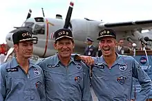 Photographie en couleur des trois membres d'équipage d'Apollo 7, portant une casquette de l'Essex après leur mission.