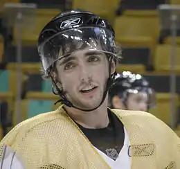 Photographie d'un joueur de hockey avec un chasuble jaune et un casque noir sur la tête
