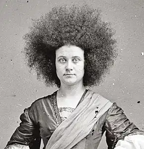 alternative1=Photographie;, portrait trois quart d'une jeune femme aux longs cheveux crépus.