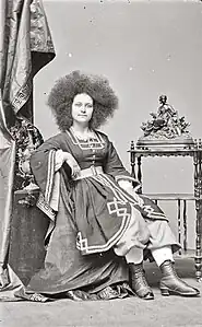 Photographie d'une jeune femme assise aux longs cheveux crépus.