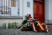 Fleurs et bougies au sol, et messages de soutiens sur le mur de l'ambassage de Belgique à Varsovie.
