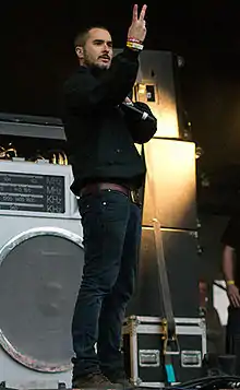 Photo d'un homme habillé en noir sur une scène qui lève le bras.