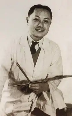 Portrait en noir et blanc de Zhang Chongren posant avec ses instruments de peintre.