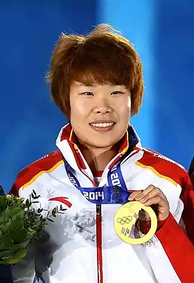 Zhou Yang souriante, tenant une médaille d'or.