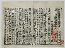 Page légèrement abimée recouverte de symboles chinois à l'encre noire et rouge.
