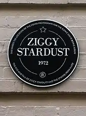 Plaque noire ronde apposée sur un mur extérieur et portant l'inscription « Ziggy Stardust, 1972 ».
