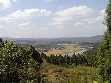 Photographie d'un paysage dans le nord du bassin du Sichuan. Le premier plan fait place à une forêt, puis vient une large plaine dans laquelle coule un cours d'eau.