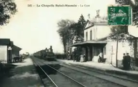  Carte postale en noir et blanc représentant l'arrivée d'un train à vapeur devant l'ancienne gare.